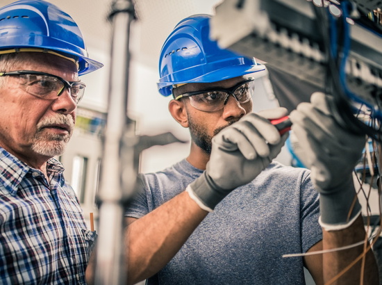 PEAG Transfer vermittelt Fachkräfte: Das Bild zeigt zwei Techniker mit Schutzhelm bei der Arbeit, älterer Vorgesetzter und sein Mitarbeiter.
